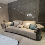 Cream Curved Leather Sofa with Dark Green Fan-Stitched Panels and Laced Edge Details